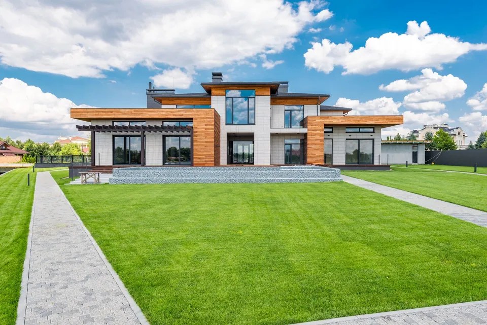 Maison contemporaine à grandes baies vitrées et bardage en bois devant une pelouse entretenue